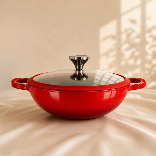 Red enameled cast iron casserole dish with a glass lid on a beige background