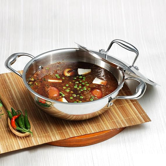 Stainless steel kadai with soup on a wooden mat