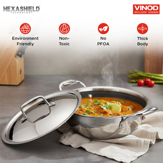 Vinod cookware with food inside on a gray surface, featuring Hexashield technology icons.
