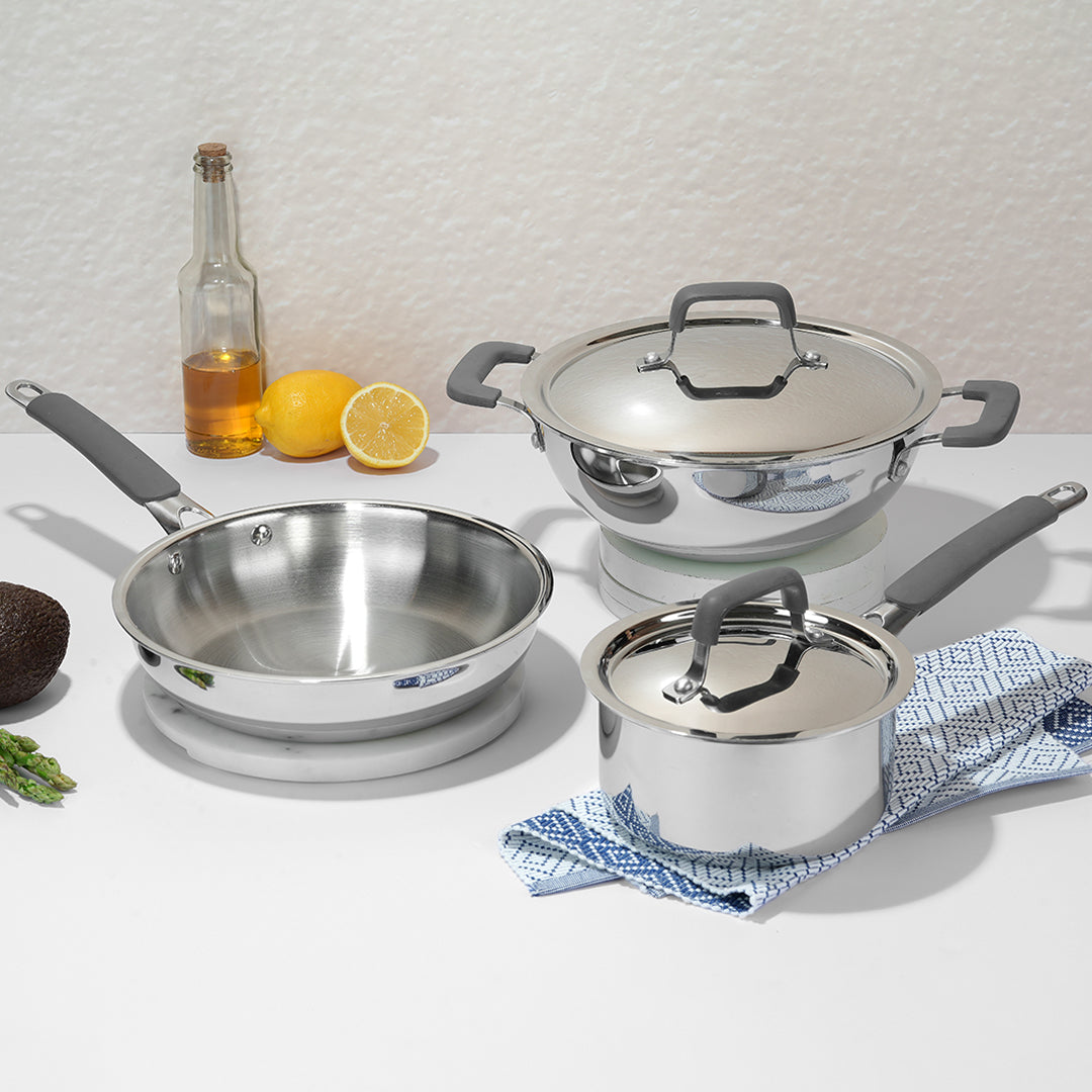 Set of stainless steel cookware with gray handles on a white surface.