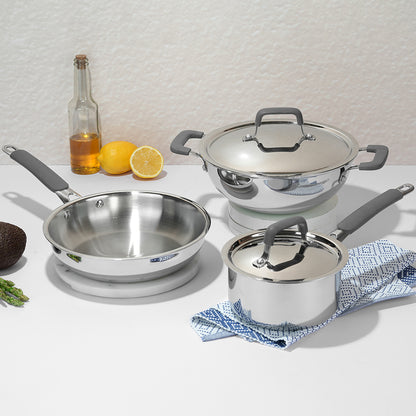 Set of stainless steel cookware with gray handles on a white surface.