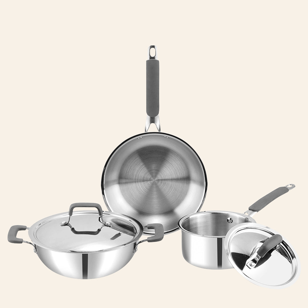 Set of stainless steel cookware including a frying pan, saucepan, and pot on a beige background