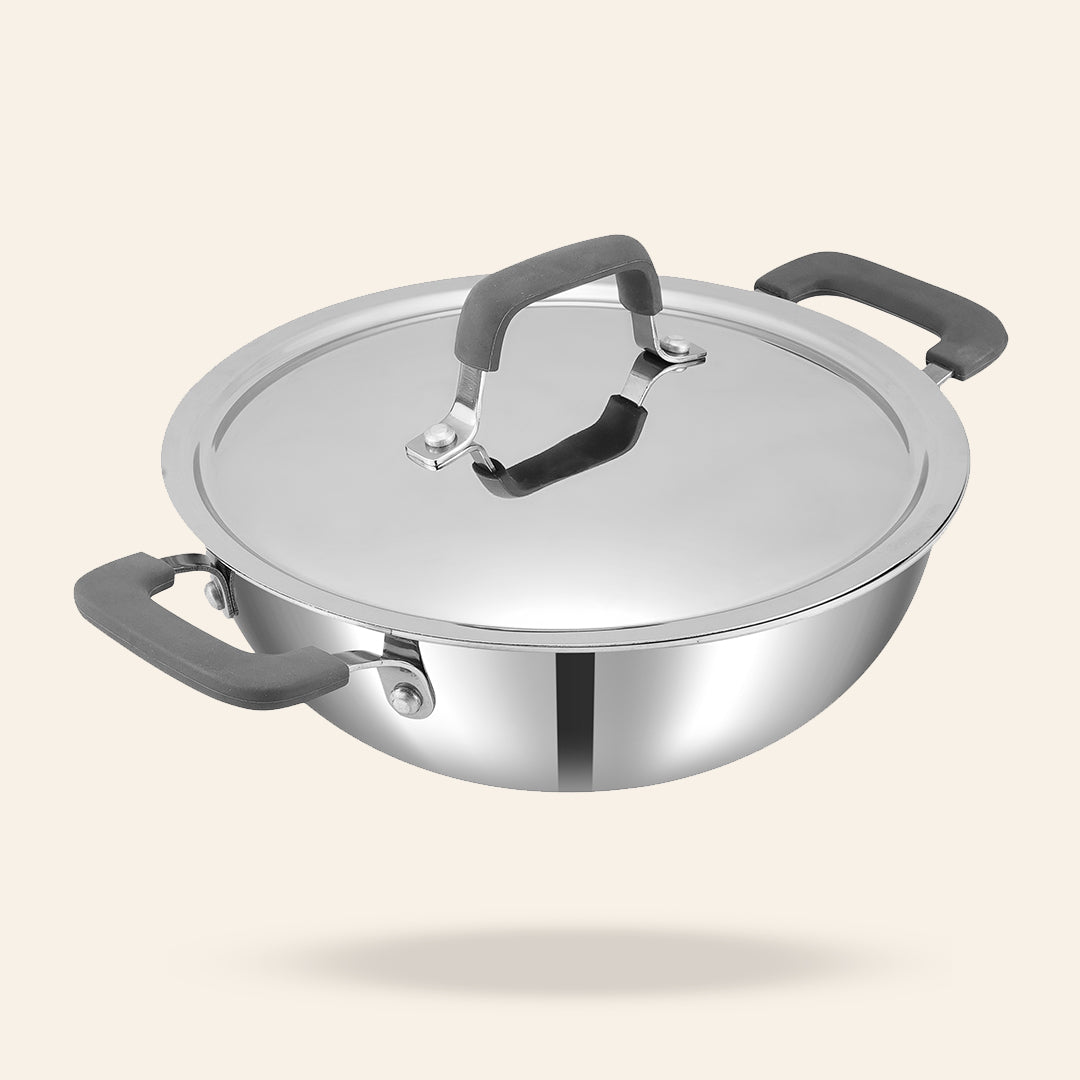 Stainless steel wok with glass lid on a light beige background
