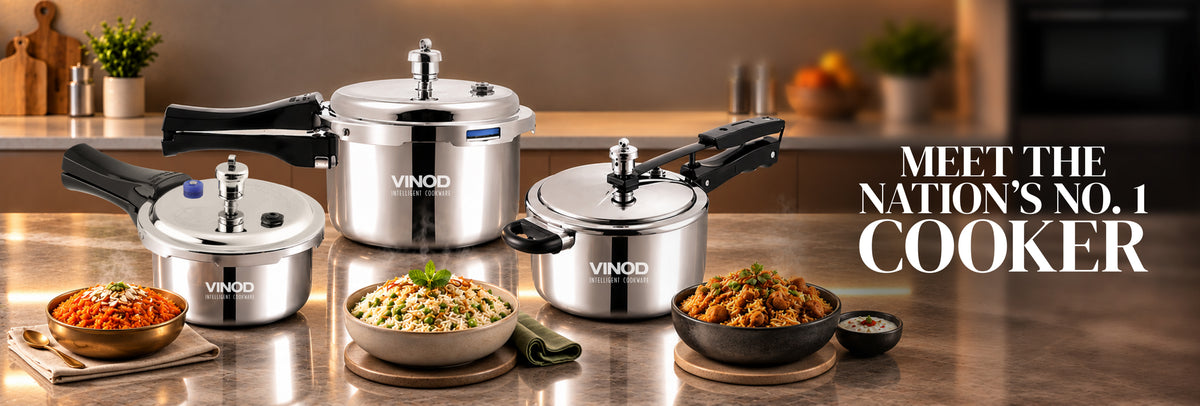Four stainless steel pressure cookers with black handles and lids are arranged on a kitchen countertop with bowls of prepared food. The brand name VINOQ is visible on the cookers.