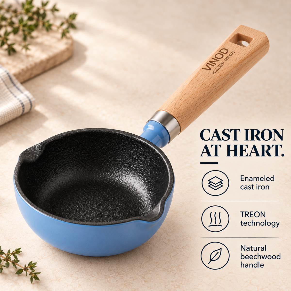 A blue and black cast iron saucepan with a natural wood handle, shown on a beige surface with decorative herbs and text highlighting product features.