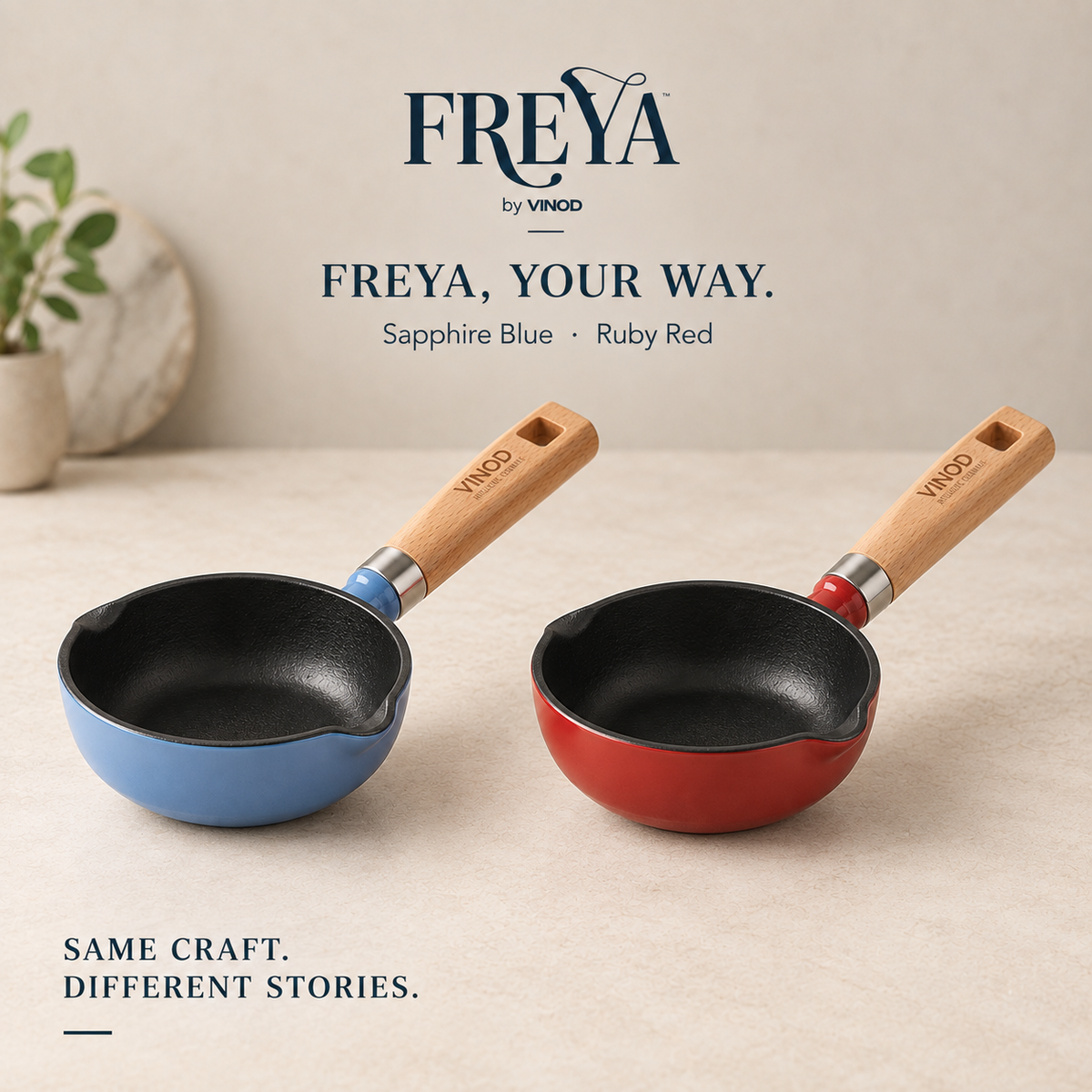 Two small cast iron tadkapan with wooden handles, one in Sapphire Blue and one in Ruby Red, displayed on a beige surface with brand text and a small plant in the background.