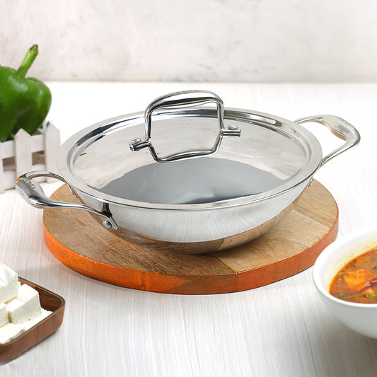A silver-colored Vinod Platinum triply stainless steel kadai with a lid, displayed on a wooden surface.
